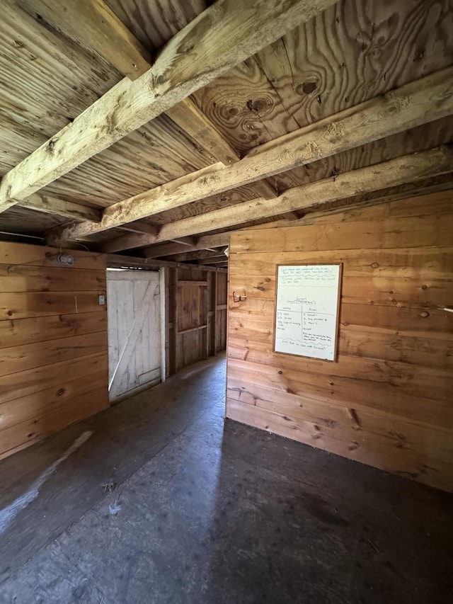 bonus room featuring beam ceiling and wooden walls