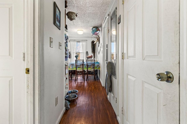 corridor with dark wood-type flooring and a textured ceiling