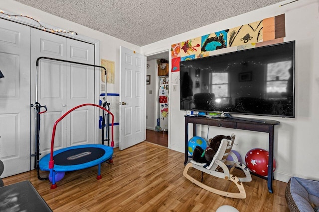 rec room featuring wood-type flooring and a textured ceiling