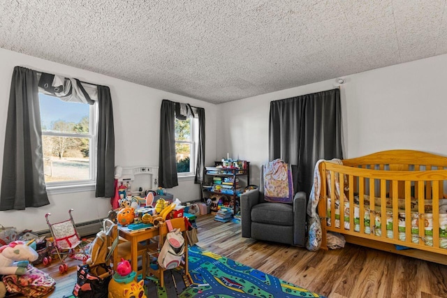 bedroom with hardwood / wood-style floors, a nursery area, and a textured ceiling