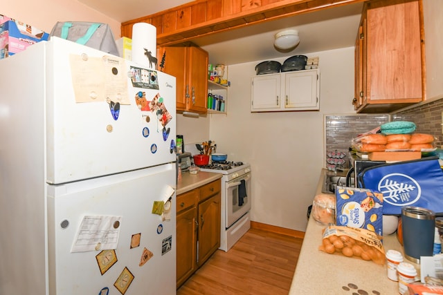 kitchen with tasteful backsplash, white appliances, and light wood-type flooring