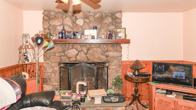 living room featuring ceiling fan, wood walls, and a fireplace