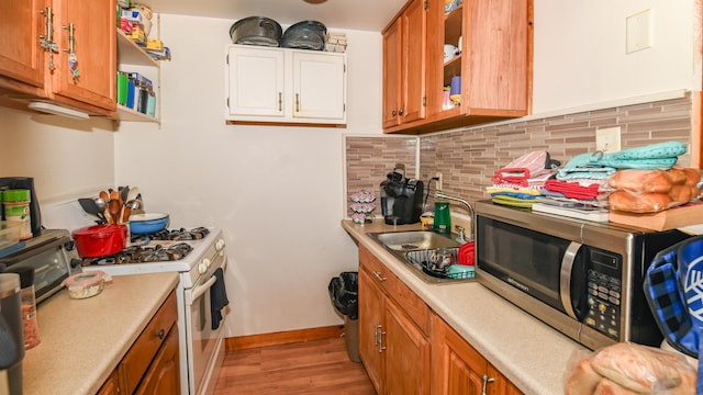 kitchen featuring decorative backsplash, light hardwood / wood-style flooring, sink, and gas range gas stove