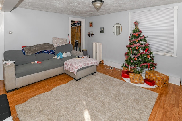 living room with a textured ceiling, hardwood / wood-style flooring, and radiator