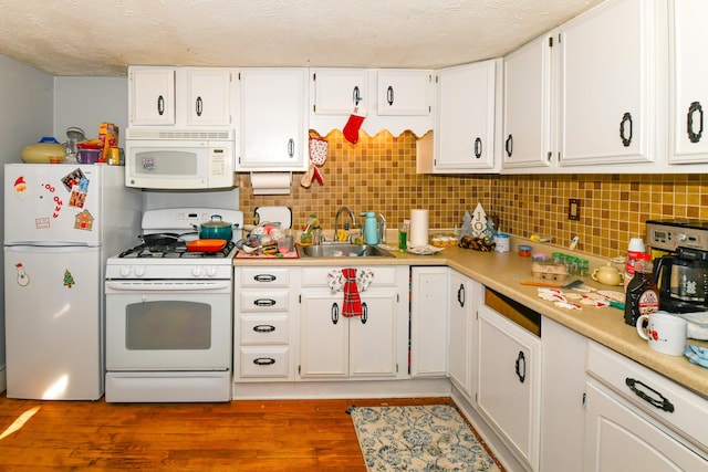 kitchen with white cabinetry, sink, white appliances, and hardwood / wood-style flooring