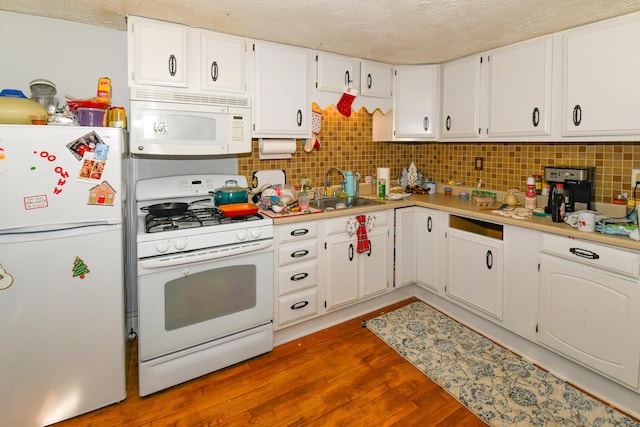 kitchen with white cabinetry, wood-type flooring, and white appliances