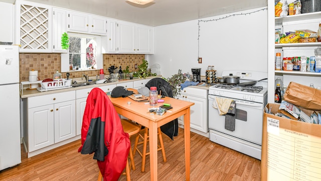 kitchen with light hardwood / wood-style floors, white appliances, sink, and white cabinetry