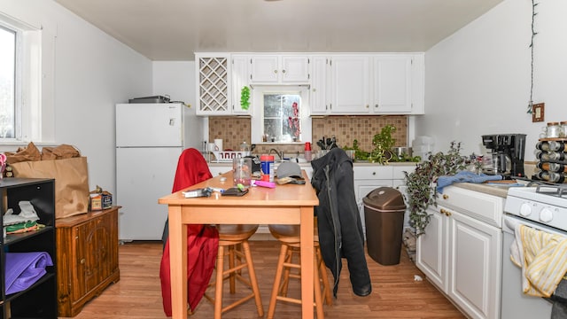 kitchen with light wood-type flooring, white appliances, and white cabinetry