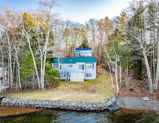 back of property with a deck with water view and a yard