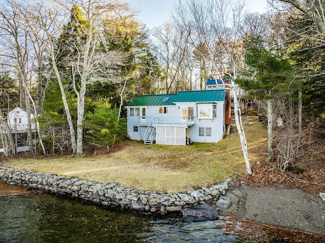 back of house with a deck with water view and a yard