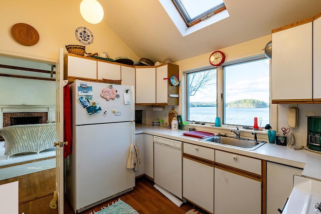 kitchen featuring white cabinets, white appliances, lofted ceiling with skylight, and sink