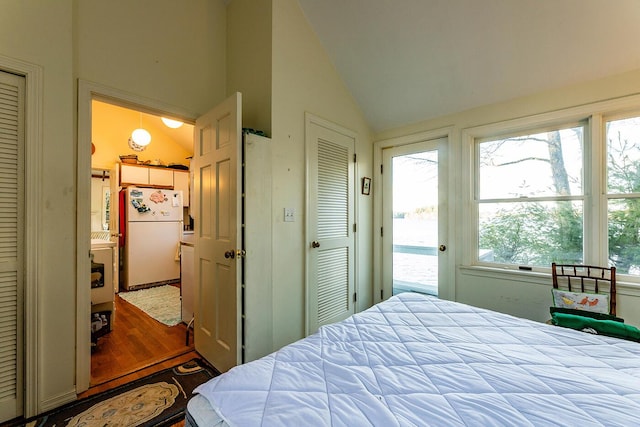 bedroom with a closet, hardwood / wood-style floors, lofted ceiling, and white refrigerator