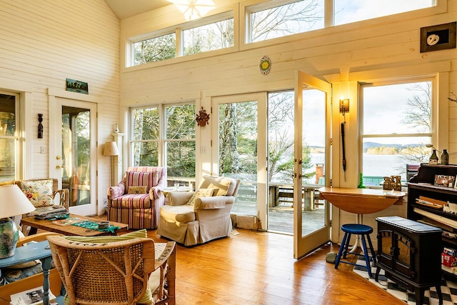 sunroom / solarium with a water view, vaulted ceiling, and a wealth of natural light