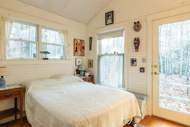 bedroom with hardwood / wood-style flooring, wooden walls, and vaulted ceiling