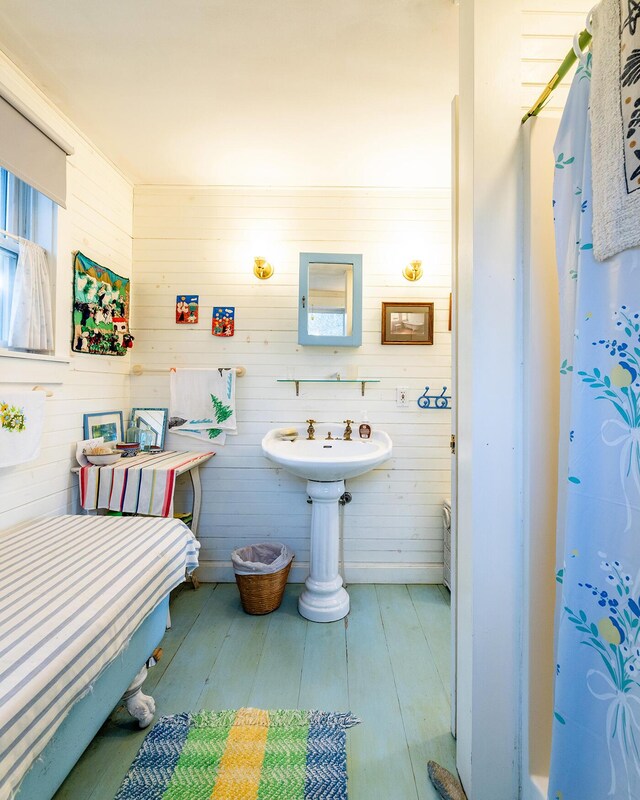 bathroom with wood walls, sink, and hardwood / wood-style flooring