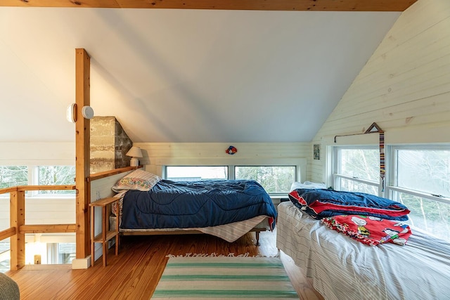 bedroom featuring wooden walls, wood-type flooring, and vaulted ceiling