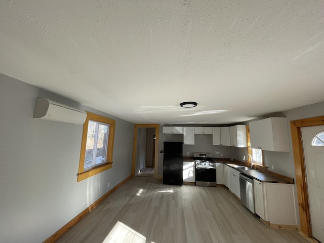 12 Main St, Sanford, ME 04083 - kitchen with appliances with stainless steel finishes, a wall mounted air conditioner, a sink, dark countertops, and white cabinetry