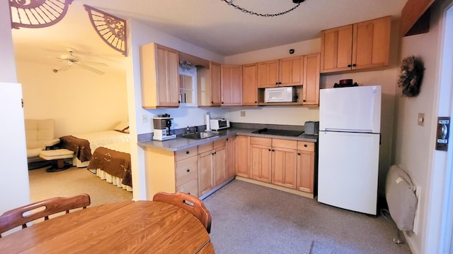 kitchen with light brown cabinets, white appliances, sink, ceiling fan, and light colored carpet