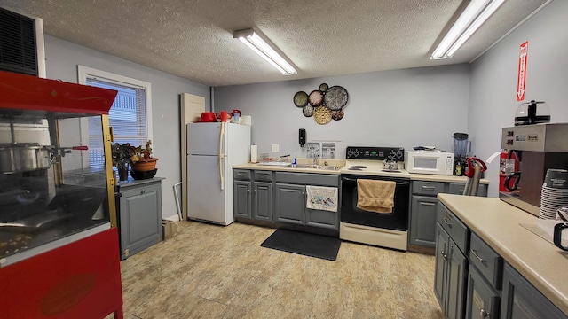 kitchen with a textured ceiling, gray cabinetry, light hardwood / wood-style flooring, and white appliances