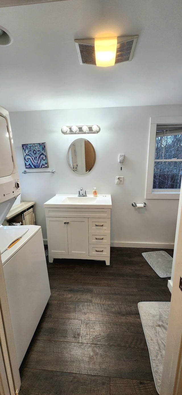 bathroom with wood-type flooring, vanity, and stacked washer / dryer