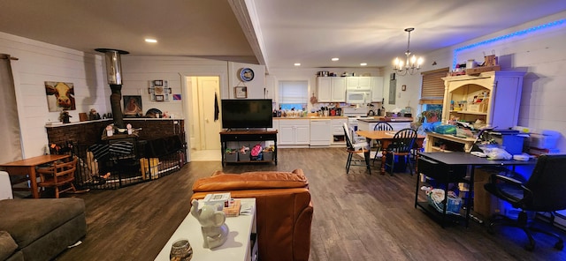 living room with a notable chandelier, dark hardwood / wood-style floors, and a wood stove