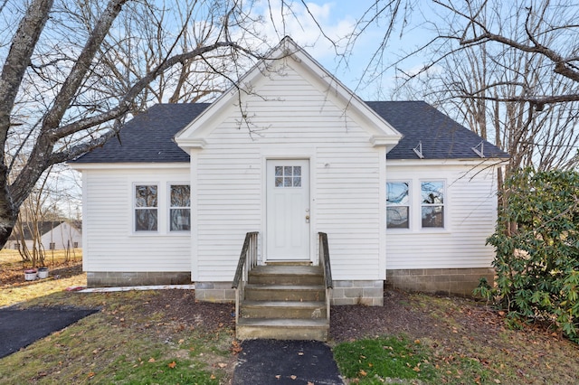 bungalow-style home with entry steps and roof with shingles