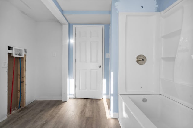 full bath with baseboards, a washtub, and wood finished floors