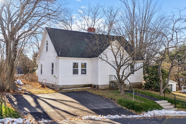 cape cod-style house featuring a chimney and roof with shingles