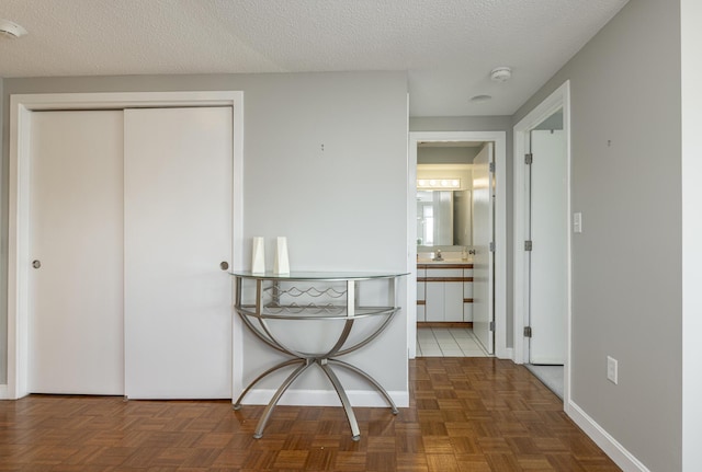 hall with dark parquet floors, sink, and a textured ceiling