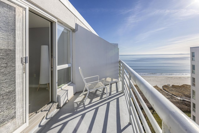 balcony featuring a view of the beach and a water view