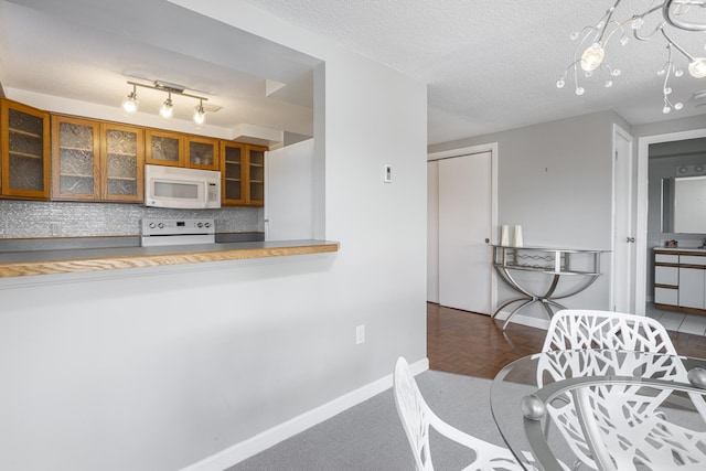 kitchen featuring a textured ceiling, white appliances, and backsplash