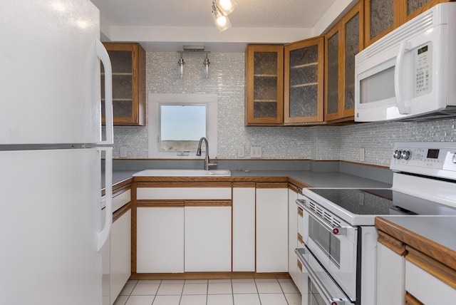 kitchen with white appliances, white cabinets, sink, light tile patterned floors, and a textured ceiling