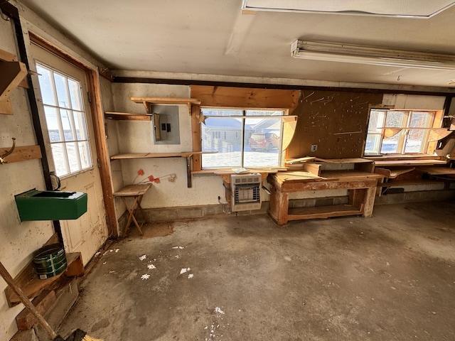 miscellaneous room featuring a workshop area, concrete floors, electric panel, and heating unit