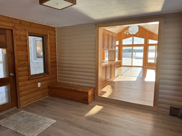 doorway featuring a chandelier, log walls, light hardwood / wood-style floors, and lofted ceiling