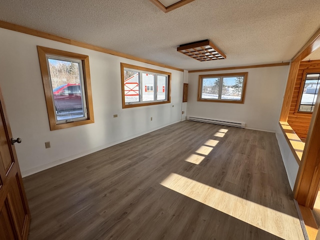 empty room with a wealth of natural light, dark hardwood / wood-style flooring, a baseboard radiator, and a textured ceiling