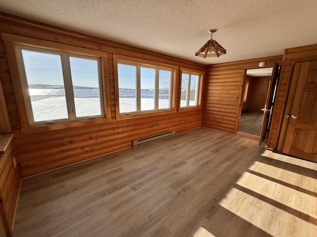 interior space with hardwood / wood-style floors, a textured ceiling, log walls, and a baseboard heating unit