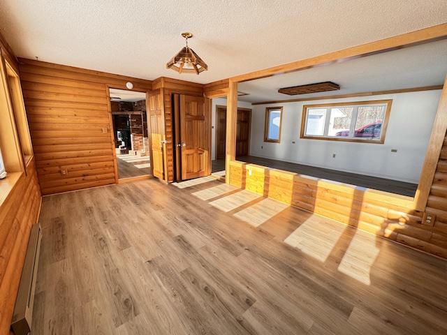 unfurnished room featuring hardwood / wood-style floors, a baseboard radiator, and a textured ceiling