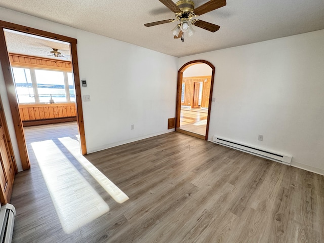 spare room featuring a textured ceiling, hardwood / wood-style flooring, ceiling fan, and a baseboard heating unit