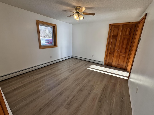 spare room with ceiling fan, a baseboard heating unit, a textured ceiling, and light hardwood / wood-style flooring