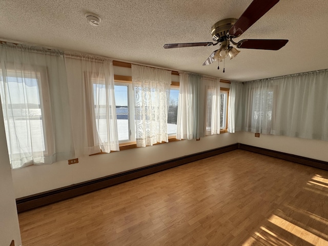 unfurnished room with ceiling fan, wood-type flooring, a textured ceiling, and a baseboard heating unit