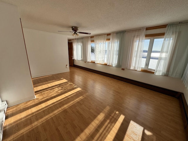 empty room featuring ceiling fan, wood-type flooring, and a textured ceiling