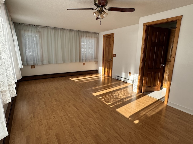 unfurnished room featuring a textured ceiling, dark hardwood / wood-style flooring, ceiling fan, and a baseboard heating unit