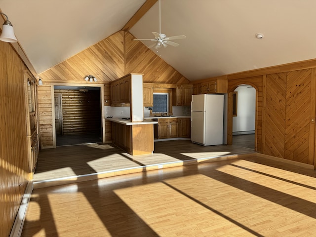 kitchen with white fridge, light hardwood / wood-style floors, and wooden walls