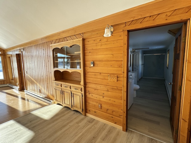 hall featuring baseboard heating, wood walls, and light hardwood / wood-style flooring