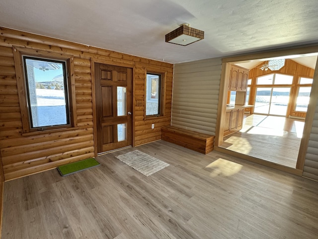 entryway with light hardwood / wood-style floors, a textured ceiling, and log walls