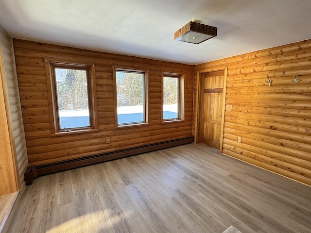 empty room featuring rustic walls, light hardwood / wood-style flooring, and a baseboard radiator