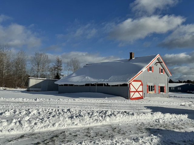 snow covered back of property featuring an outdoor structure