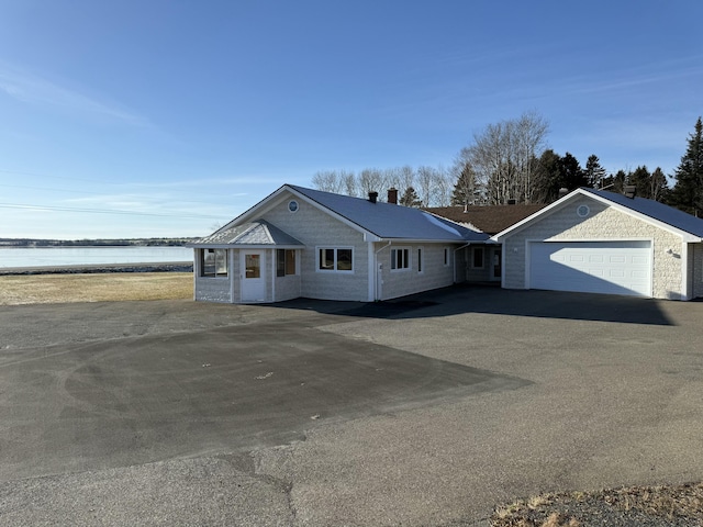 single story home with a garage and a water view