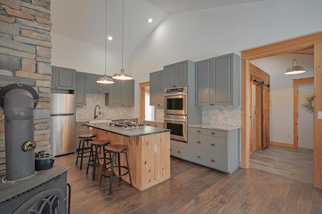 kitchen featuring stainless steel appliances, a center island, tasteful backsplash, and high vaulted ceiling