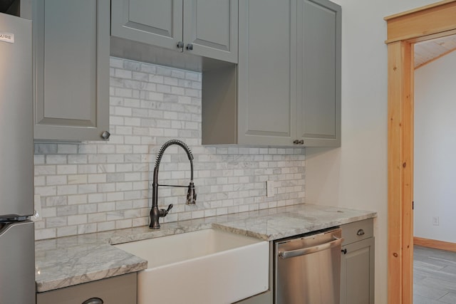 kitchen featuring light stone counters, sink, gray cabinetry, and stainless steel appliances